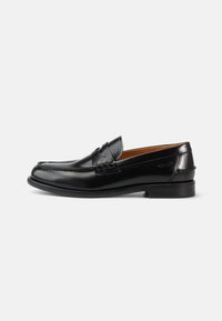 Mustad mustad nahast loafers, millel on sile viimistlus, ümar varvas ja dekoratiivne õmblus peal. Madal kann, mis omab klassikalist profiili.