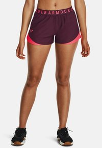 Krátké sportovní šortky tmavě fialové barvy s jasně růžovými akcenty, vybavené elastickým pasem s nápisem „Under Armour“.