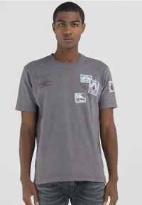 Camiseta de algod�ón gris con mangas cortas, cuello redondo y varios estampados impresos en detalles azules, rosas y marrones. Dobladillo desgastado en las mangas.