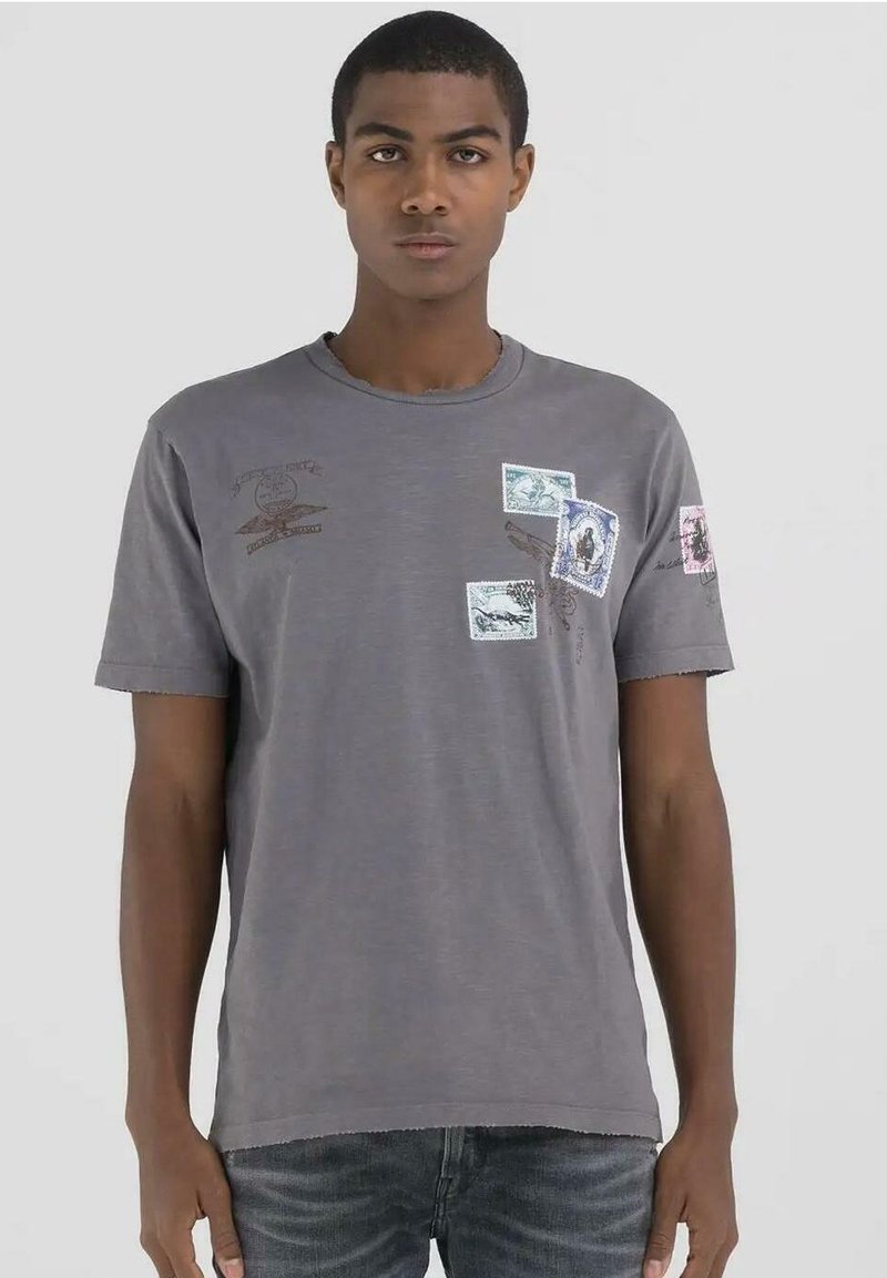 Camiseta de algodón gris con mangas cortas, cuello redondo y varios estampados impresos en detalles azules, rosas y marrones. Dobladillo desgastado en las mangas.