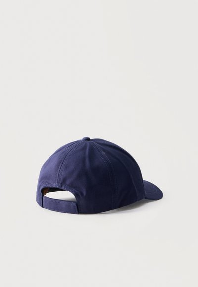 Casquette de baseball bleu marine vue de dos avec sangle réglable, posée sur une surface blanche.