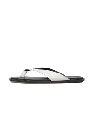 Sandalia de suela plana negra con una amplia tira de cuero blanca y separador de dedos, diseño minimalista y moderno.