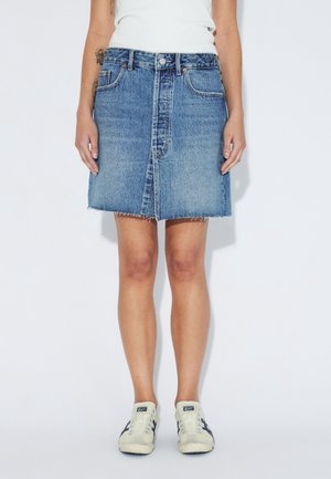 Lysblå denims nederdel med lige snit, frynset kant, forlommer og knaplukning, kombineret med cremefarvede sneakers.