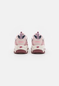 Baskets roses et blanches avec une semelle épaisse, en mesh et en daim, dotées d'une languette de talon rayée et du logo "SKECHERS" à l'arrière.