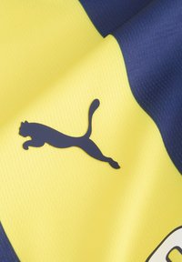 Puma športový dres v žltej a námorníckej modrej farbe, s textúrovanou tkaninou a výrazným námorníckym logom skáčucej mačky na žltej časti.