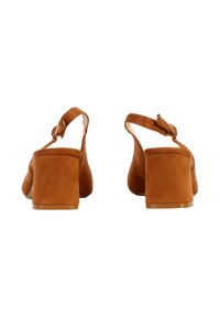 Sandales à talons bas en daim marron avec brides à la cheville et boucles métalliques, vues de dos sur un fond blanc.