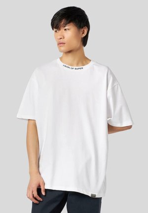 T-shirt bianco oversize con testo "VISION OF SUPER" sul colletto. Tessuto in cotone con maniche corte e una vestibilità rilassata.