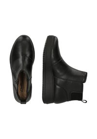 Botas de tobillo de cuero negro con un acabado suave, cremallera lateral y suela de goma texturizada. Presentan pequeños acentos de tachuelas y paneles elásticos.