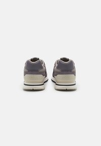 Adidas trkačke tenisice s ljubičastim gornjim dijelom, mrežastim panelima, bež detaljima i crnim potplatom. Imaju logo na peti i teksturirani dizajn.