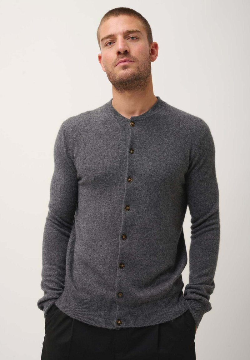 Šedý vlněný kardigan s kulatým výstřihem, sedm hnědých knoflíků vpředu, slim fit, žebrované manžety a lem, jemná textura.