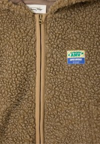 Giacca in pile marrone con texture, zip frontale, etichetta "La Maison AMV Super Vintage" sul petto e etichetta al collo "American Vintage A.M".
