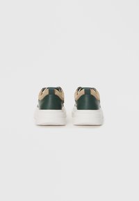 Green leather sneakers with beige accents, rounded white rubber sole, and suede detailing at the back. Laced design with pull tab.