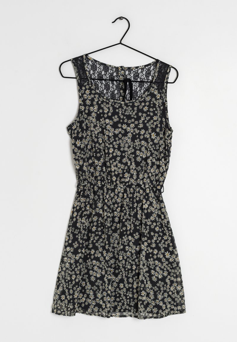 Robe fleurie à fond noir, ornée de motifs de marguerites blanches, sans manches, avec des détails en dentelle au niveau du col et une taille élastique.