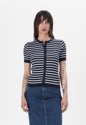 Marineblå og hvit stripete kortermet cardigan med knappfront, ribbet tekstur og rund utringning. Kombinert med et denimskjørt.