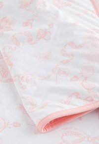 Lightweight cotton fabric with a white background, featuring a pink floral and ribbon pattern. Accented with pink hem and soft texture.