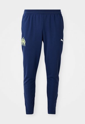 Pantaloni sportivi blu navy con una vestibilità affusolata, caratterizzati da un tessuto testurizzato, logo giallo sulla coscia sinistra e logo Puma sul lato destro.