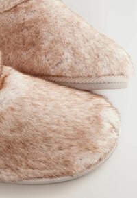Faux-Fellslipper in Hellbraun mit einer weichen, strukturierten Oberfläche. Runde Zehen und gestickte Ränder, mit einem dezenten Glanz.