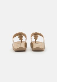 Tan sandaler med en glatt metallisk finish, åpen bakdesign og en kraftig såle. Har justerbare stropper og teksturerte detaljer.