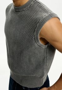 Grå stickad ärmlös tröja med ett strukturerat mönster, ribbad halsringning och armhålsony, med en åtsittande botten och en slät tygfinish.