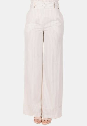 Pantaloni bianchi a vita alta con gamba larga, sottili righe verticali, bottone frontale, passanti per cintura e orli risvoltati, indossati con sandali con punta aperta.