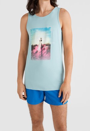 Débardeur bleu clair en mélange de coton, avec un imprimé graphique vibrant et des lignes horizontales. Associé à un short bleu, illustrant un look décontracté.