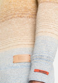Multikleuren gebreide trui met horizontale strepen in beige, bruin en lichtblauw. Heeft leren labels en een rood accentlabel.