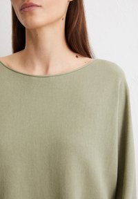 Hellgrünes, weiches Strickoberteil mit weitem Ausschnitt und lockerer Passform, das über eine glatte Textur und lange Ärmeln verfügt.
