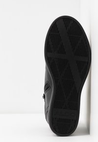 Czarne sneakersy z gumową podeszwą, z teksturowanym wzorem. Detal w postaci zamka błyskawicznego z boku i logo wytłoczone na pięcie. Gładki materiał wierzchni.