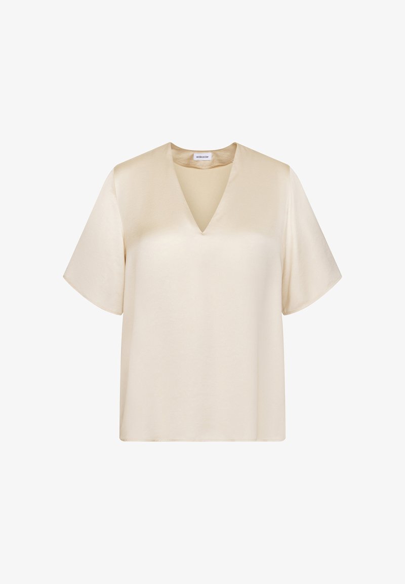 Blouse couleur crème à manches courtes avec col en V et tissu lisse semblable au satin, présentée sur fond blanc.