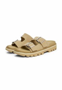Sandalias de gamuza beige con dos hebillas ajustables de plata, plantilla moldeada y suela de goma gruesa que presenta un patrón de relieve.