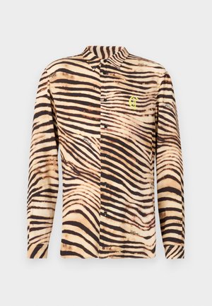 Ilgais rankovės marškinis su dryžuotu tigro ornamentu šviesiai rudos ir tamsiai rudos spalvų, su šviesiai žaliu logotipu ir juodais mygtukais.