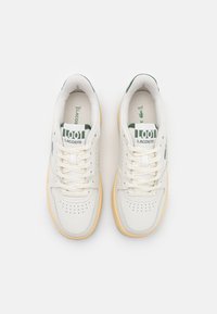 Valged nahast tennisetossud roheliste detailidega, perforatsioonidega varvas, ümmargused paelad ja kummist talla. Lacoste logo kandmisel ja keeles.