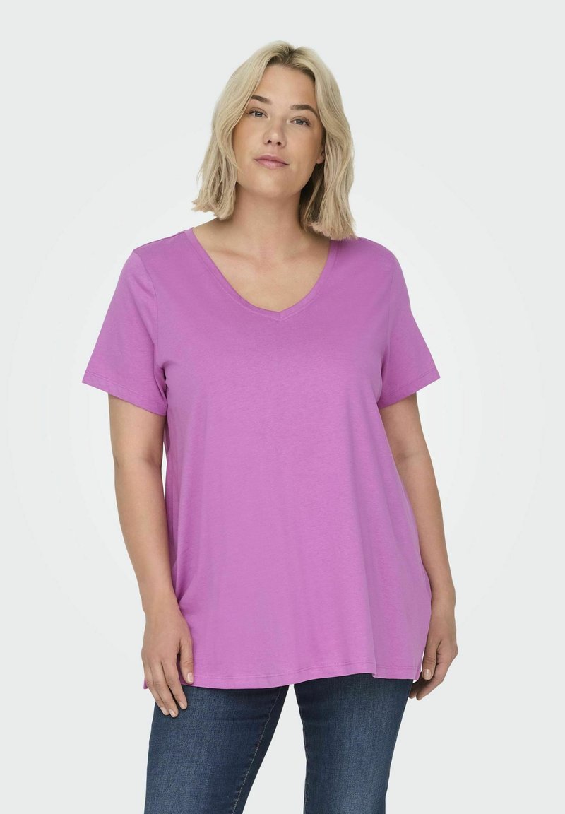 T-shirt a manica corta con scollo a V in un vivace color lavanda, dalla vestibilità ampia, realizzata in morbido cotone. Abbinato a jeans blu scuro.