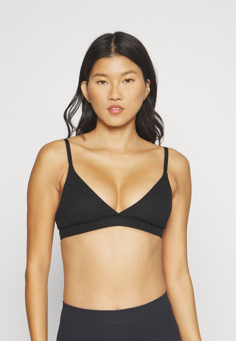 Bralette noire avec un design triangulaire, fines bretelles réglables et tissu sans couture. Style simple et minimaliste.