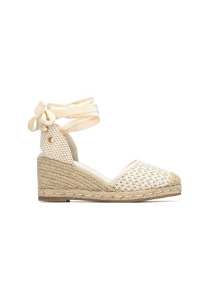 Alpargata beige con cuña, textura tejida, punta cerrada, lazo para atar en el tobillo y suela de cuerda.
