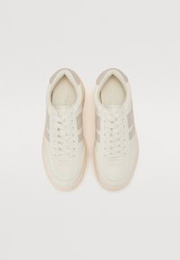 Hvite lær sneakers med beige semsket skinndetaljer og striper, rund tå, flate snørebånd og en teksturert yttersåle. Enkle, rene linjer.