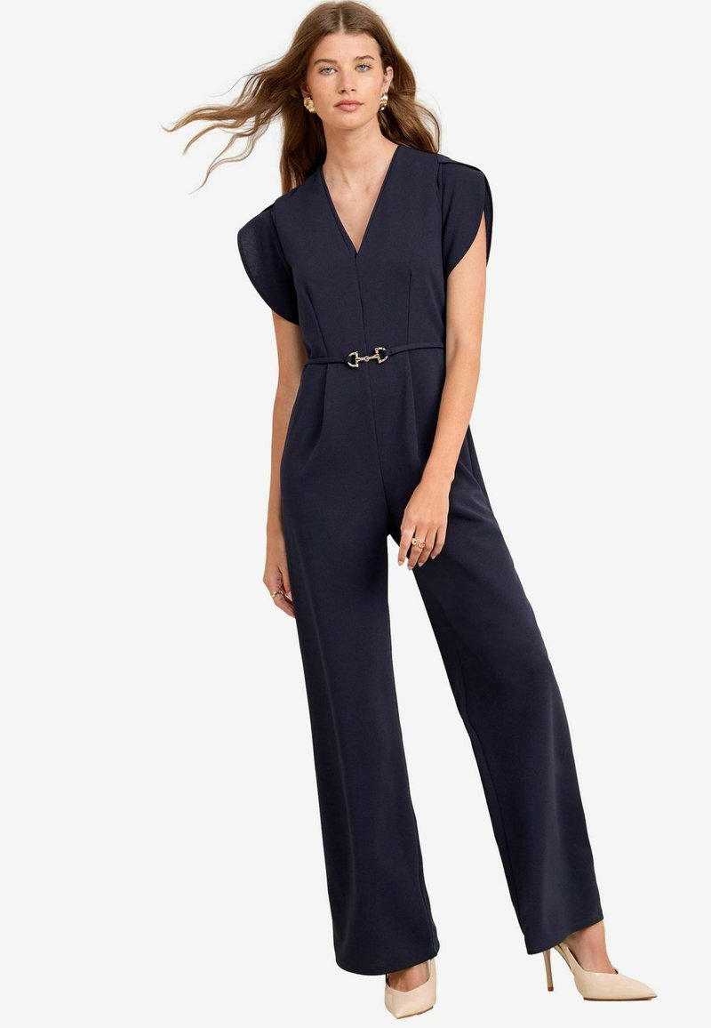 Jumpsuit blu Navy con scollatura a V, maniche corte, vita elastica con una accentuazione in metallo dorato, e pantaloni a gamba larga. Tessuto dalla texture liscia.