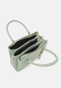 Grön läderhandväska med dubbla zipfack, guldiga detaljer och två bärhandtag. Inuti är den klädd med en svart foder.