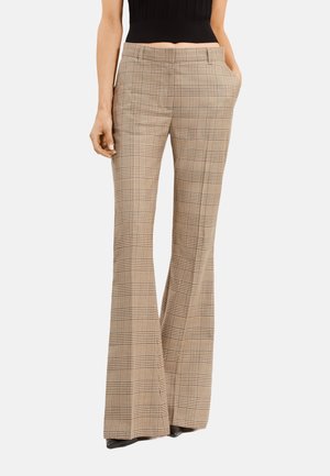 Pantalones de cuadros beige acampanados con cintura alta, que cuentan con bolsillos y un acabado suave. El patrón consiste en líneas negras finas y gruesas.