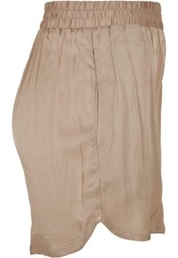 Shorts en satin beige avec taille élastique, présentant une texture lisse, des poches latérales et un ourlet légèrement arrondi.