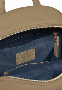 Bolso de cuero texturizado beige con interior de tela azul marino, bolsillo interior con cremallera y etiqueta de marca cosida "LAZAROTTI" dentro.