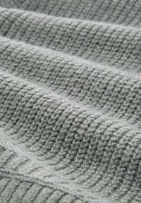 Texturiertes graues Strickgewebe mit vertikalen und horizontalen Rippmustern, das ein weiches Erscheinungsbild und eine beträchtliche Dicke aufweist.