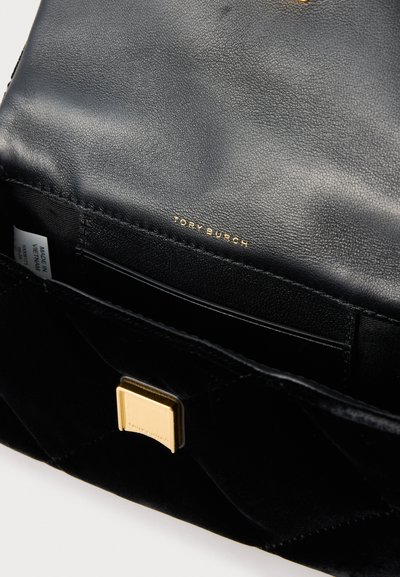 Μαύρη δερμάτινη τσάντα χειρός με υφή στην εξωτερική επιφάνεια, χρυσά μεταλλικά στοιχεία και ανάγλυφο λογότυπο. Το εσωτερικό διαθέτει πολλαπλές θήκες για κάρτες και λείο επένδυση.