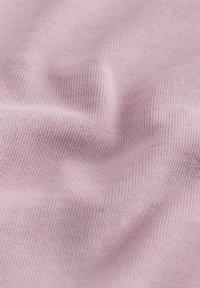 Gros plan sur un tissu tricoté doux violet clair montrant une fine texture côtelée et des plis doux.