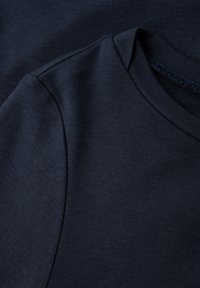 Marineblauwe katoenen T-shirts gestapeld, met een ronde halslijn, een soepele textuur en verstevigde schoudernaden voor duurzaamheid.