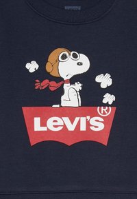 Marine sweatshirt met een cartoon hond die een duikbril en een pilotenpet draagt, met daaronder een rood Levi's logo. Het ontwerp bevat wolken en een sjaal.