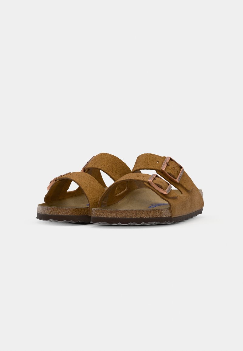Sandales en suède marron avec deux straps réglables, boucles en ton cuivre, et une semelle en liège texturée. Légères avec une semelle en caoutchouc flexible.