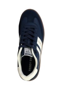 Zapatilla azul marino con franjas blancas, parte superior de ante, cierre de cordones, suela de goma y plantilla acolchada, con la marca "TEDDY SMITH".