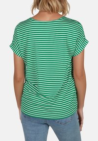 Camiseta a rayas verdes y blancas con mangas enrolladas, un cuello redondeado y un ajuste relajado, combinada con unos vaqueros de mezclilla azules.