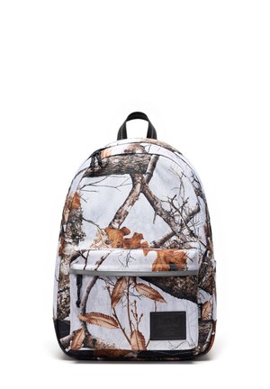 Rygsæk med hvid baggrund og et camouflage mønster med brune og grå efterårsblade og trægrene, frontlomme med lynlås og sort håndtag.